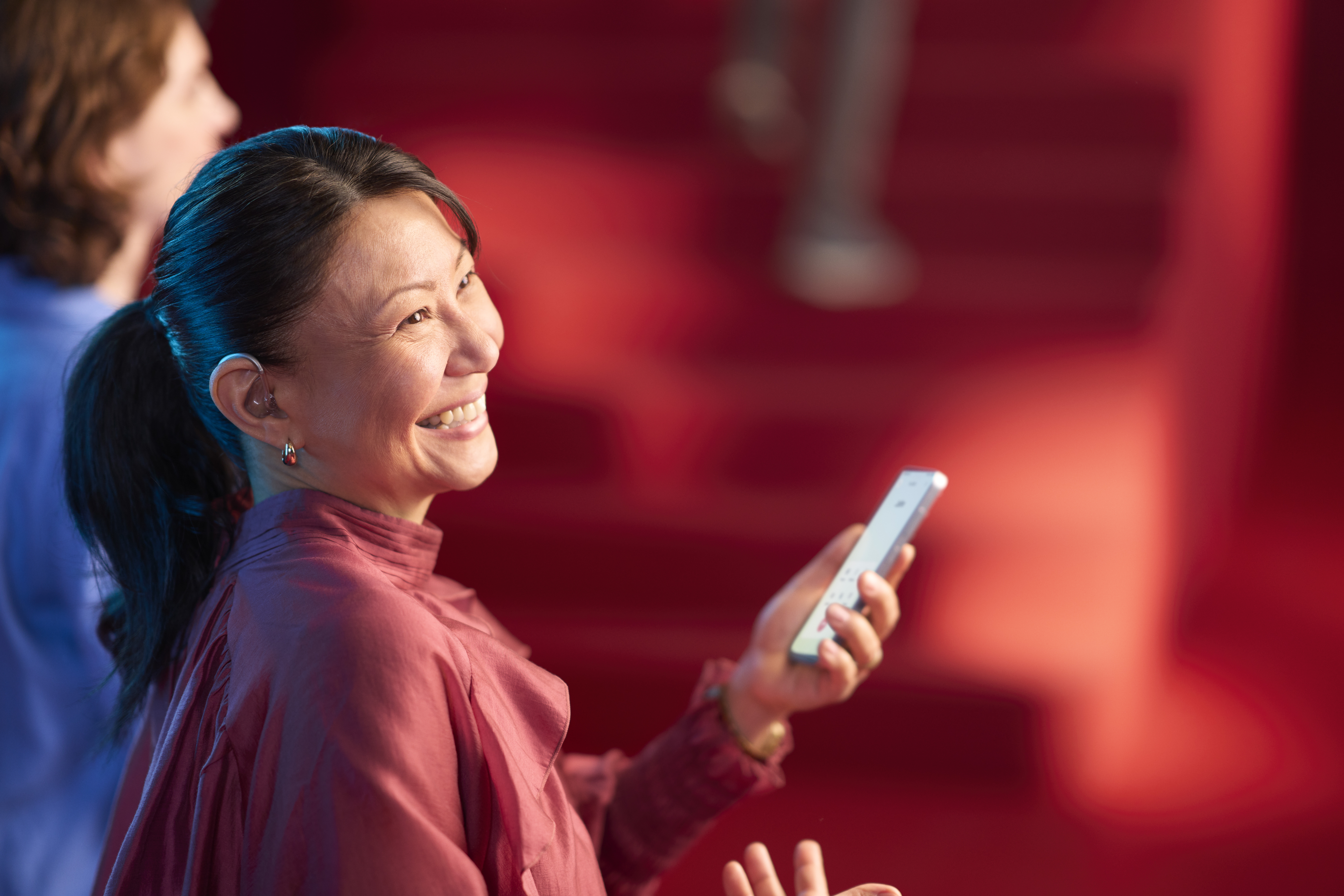 A woman picks up a hearing aid out of its charger