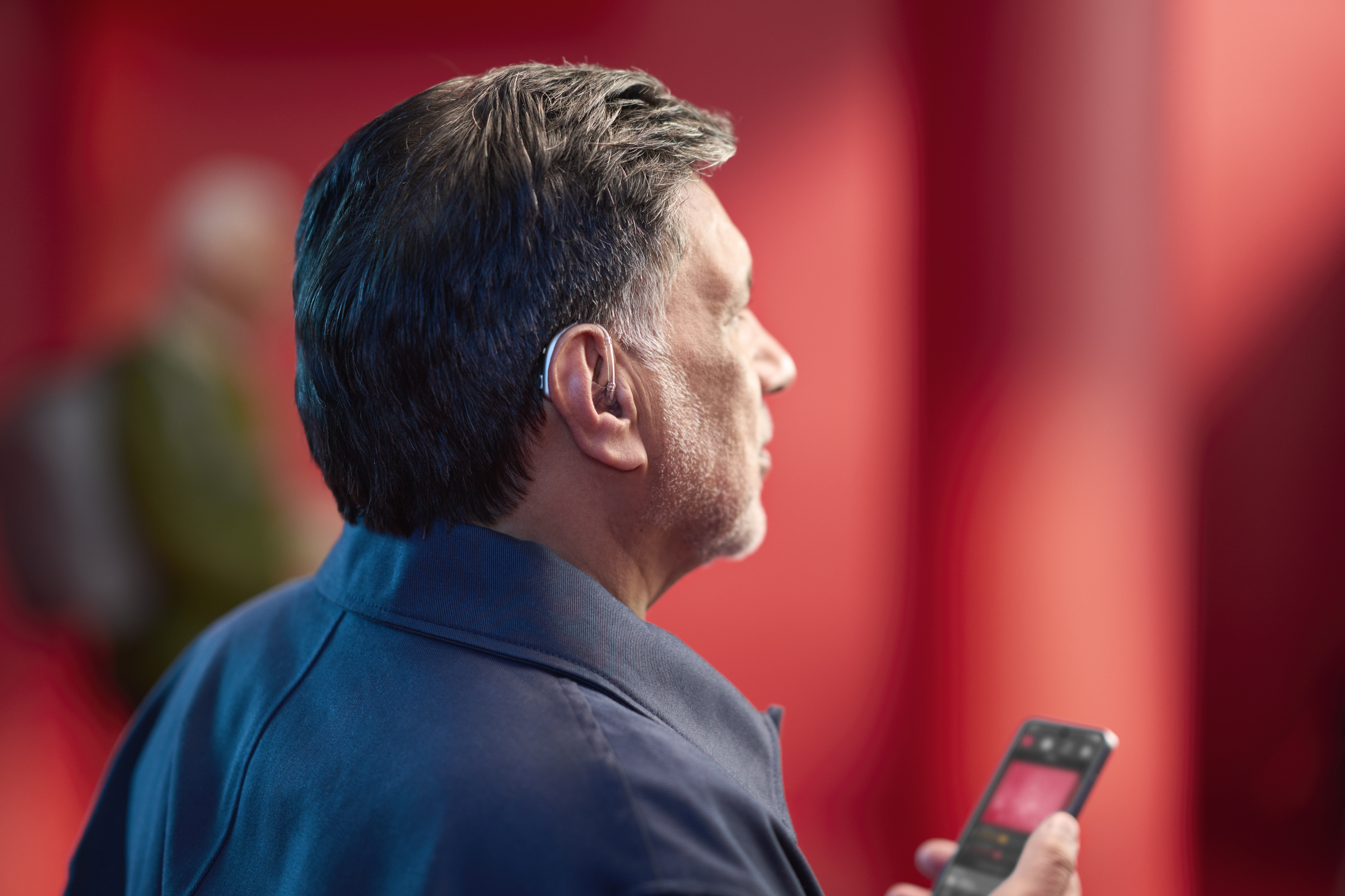 A woman picks up a hearing aid out of its charger