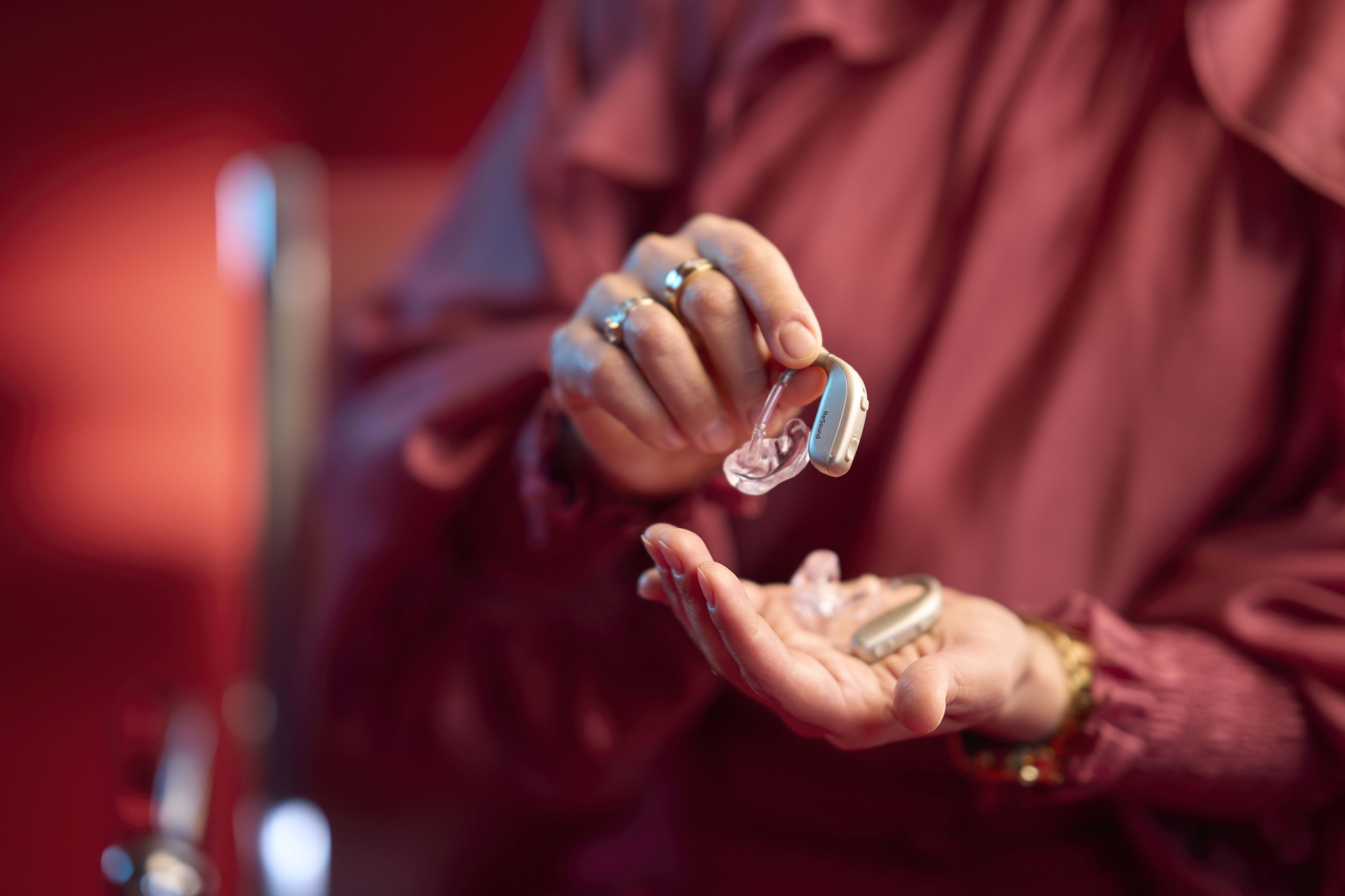 A woman arranges flowers in a vase while wearing hearing aids